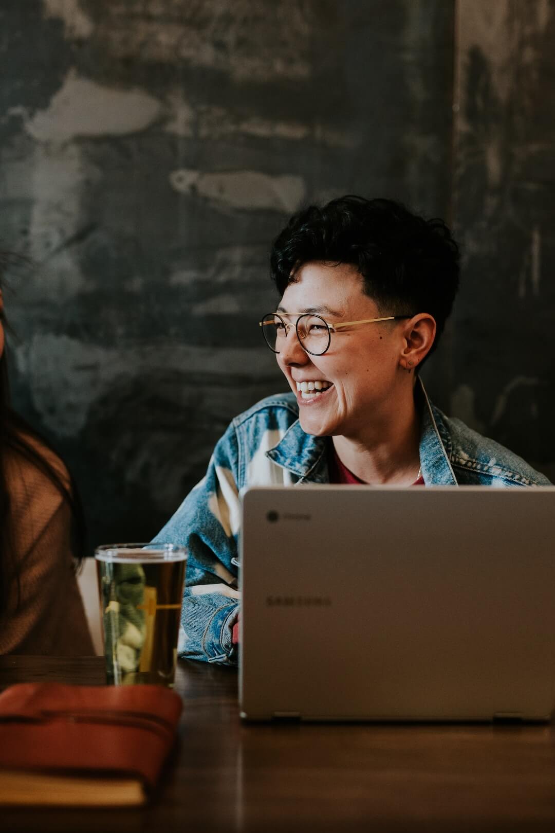 person smiling with laptop and a pint of beer